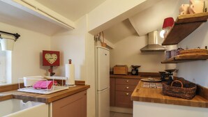 Eine kleine Küche mit Kühlschrank, Holz Arbeitsplatte und einer Uhr an der Wand.