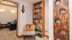 A cozy living room with a bookshelf, a decorative wall piece, and a unique wall feature with circular cutouts. - The Stables (Chester)
