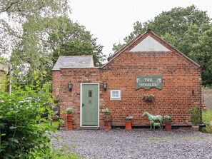 A brick building with a green door and a sign reading "The Stables". - The Stables (Chester)