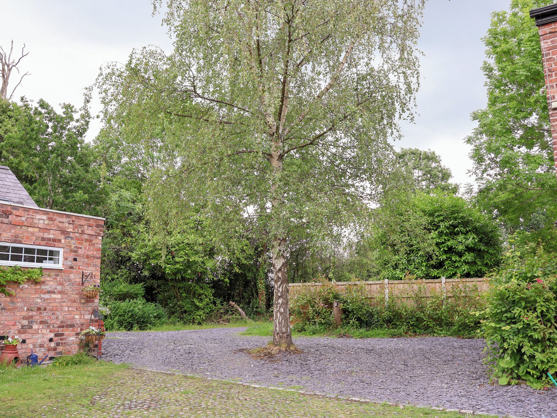 A brick building with a gravel driveway and a tree in front.