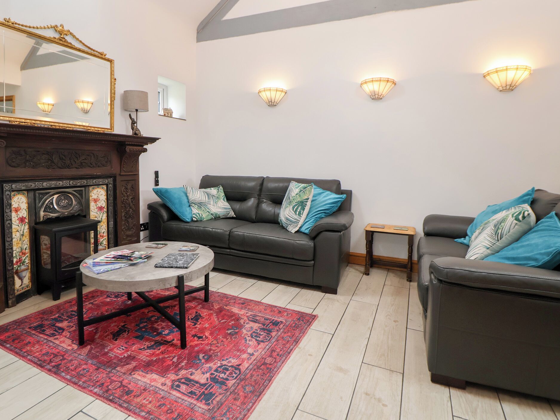 A living room with a fireplace, two sofas, a coffee table, and a patterned rug.