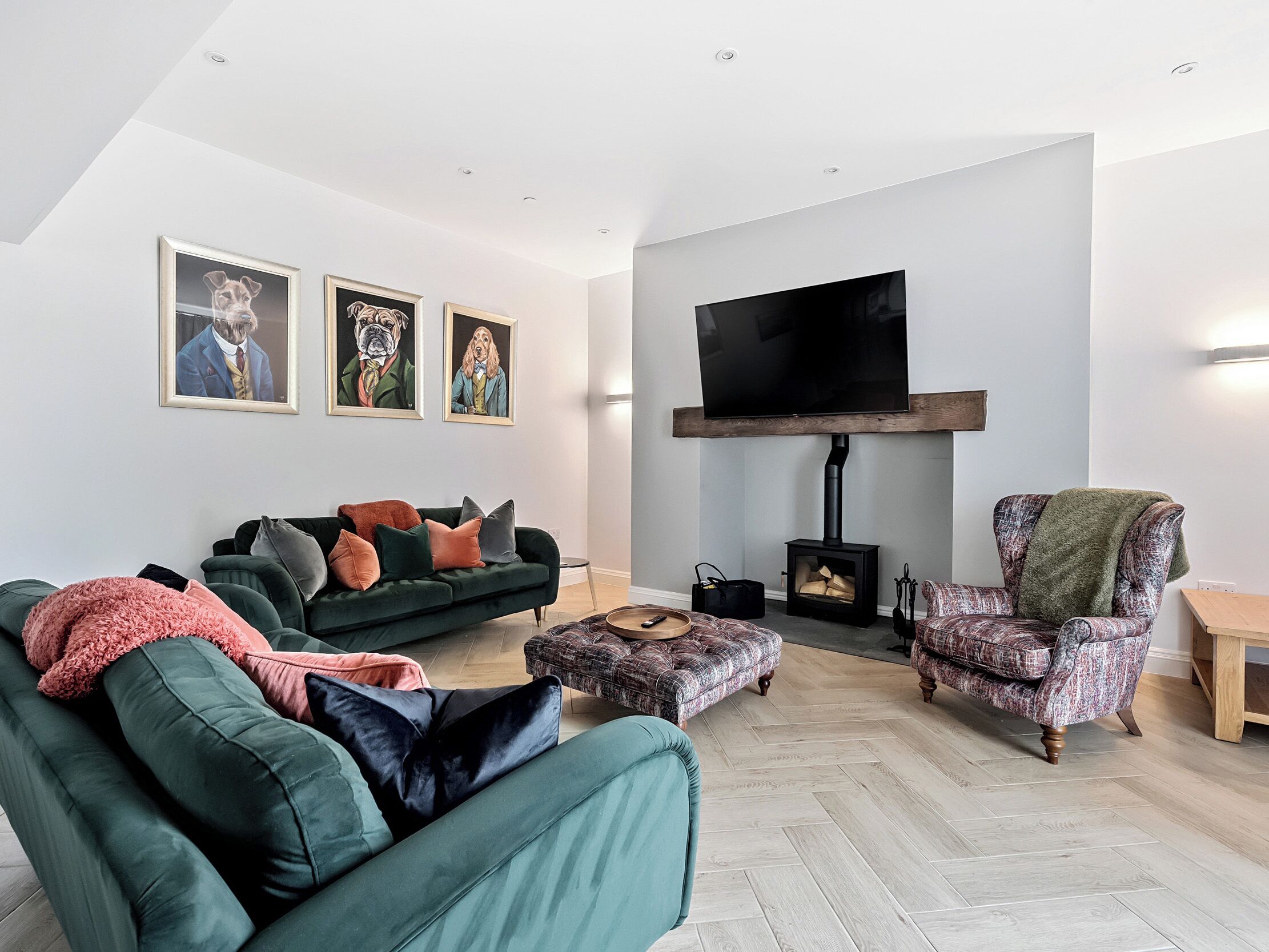 A modern living room with a green sofa, patterned armchair, and a fireplace.