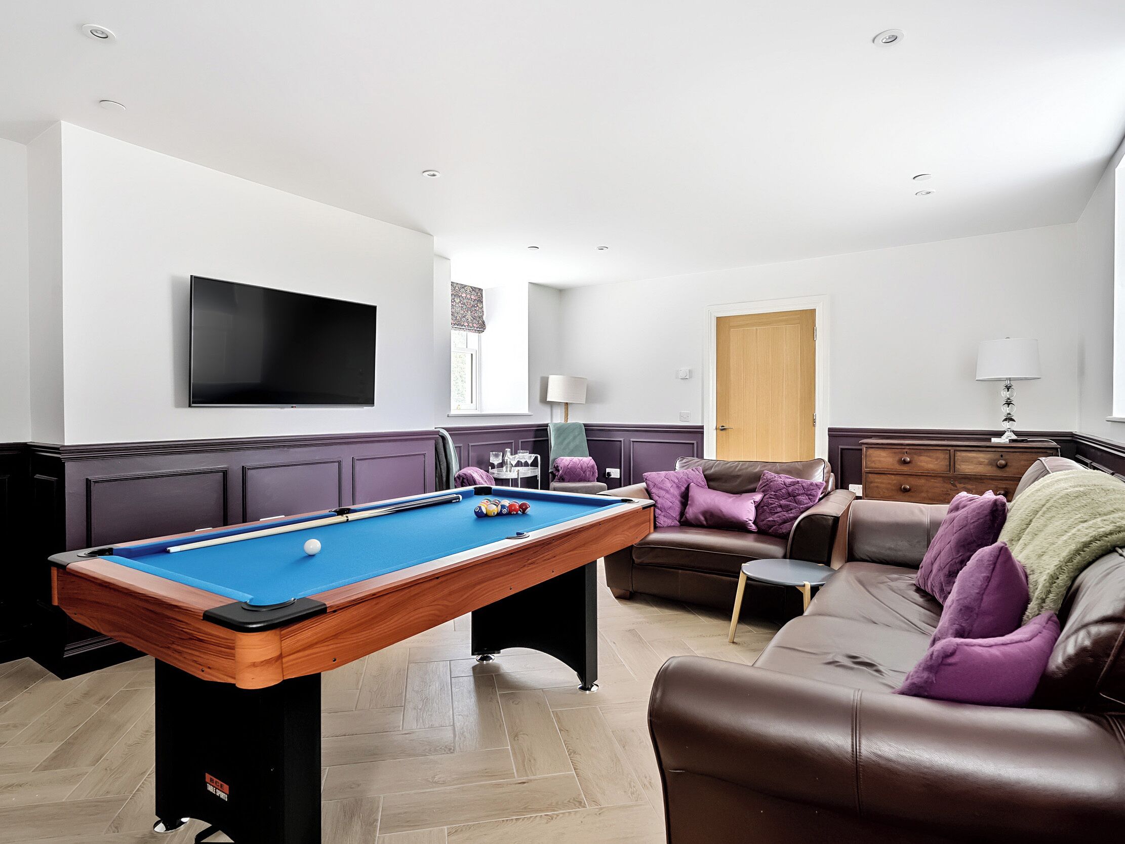 A pool table in a room with a sofa and a television.