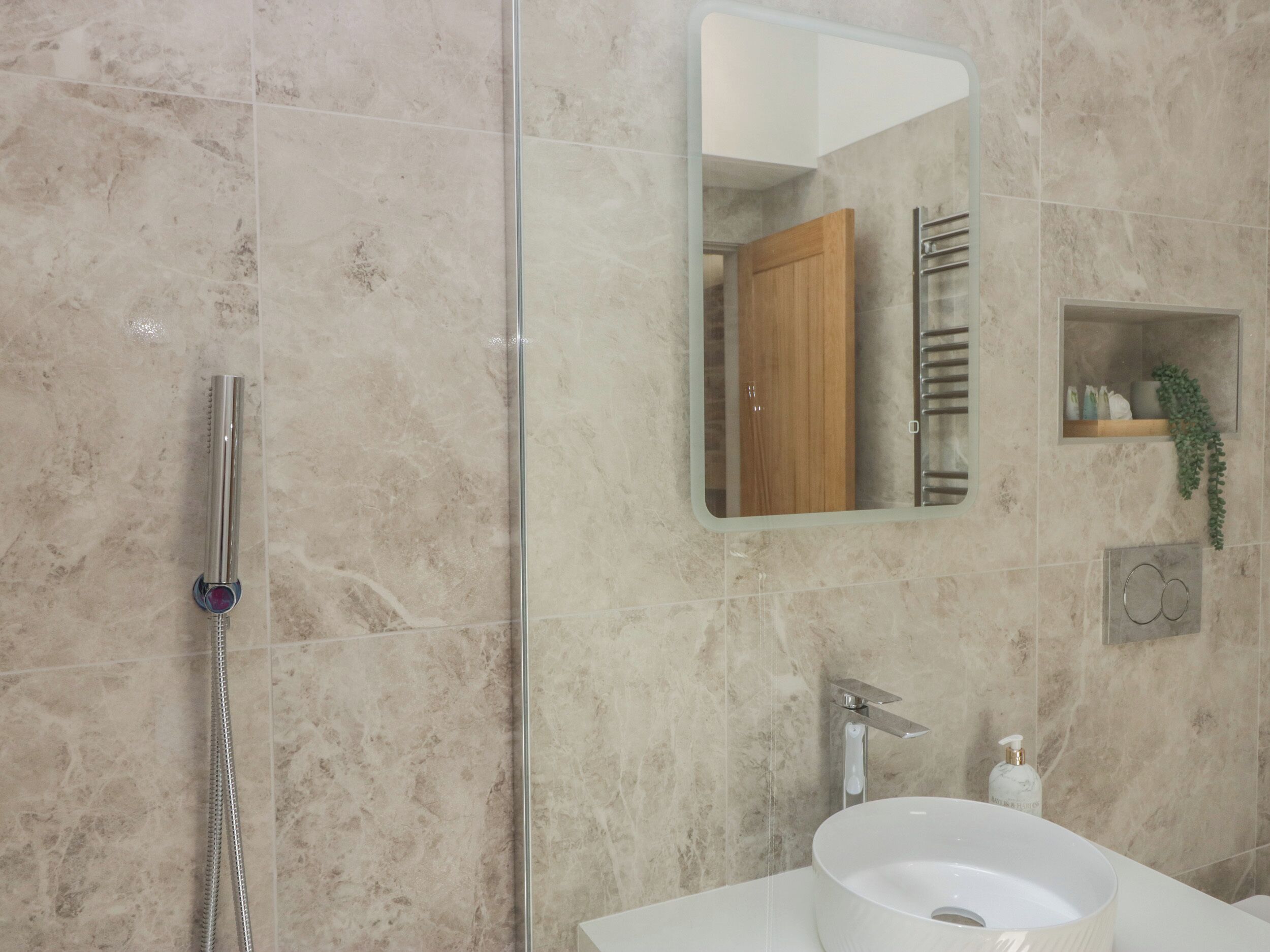 A bathroom with a glass shower enclosure, a white sink, and a mirror above the sink.