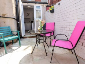 A patio with a table and two chairs, a bench, and a brick wall. - Verdo House (Blackpool)