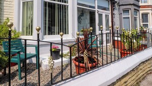 A row of terraced houses with white and grey facades, black railings with golden balls, and potted plants in front. - Verdo House (Blackpool)