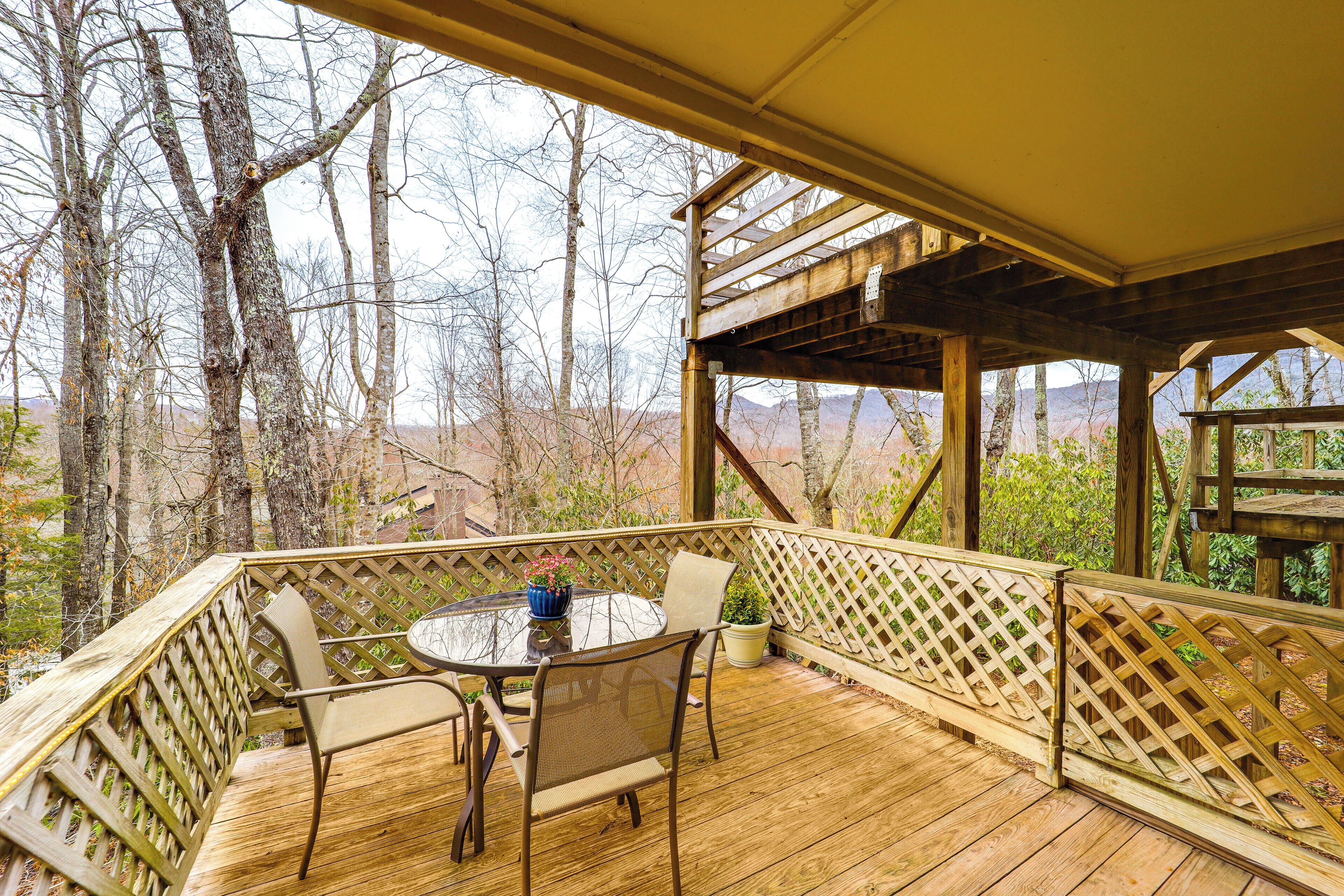 A wooden deck with a table and chairs, surrounded by a wooden fence and trees.