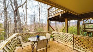 A wooden deck with a table and chairs, surrounded by a wooden fence and trees.