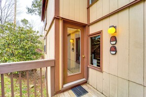 Una casa de madera con una puerta marrón, un porche pequeño y una ventana con una lámpara.