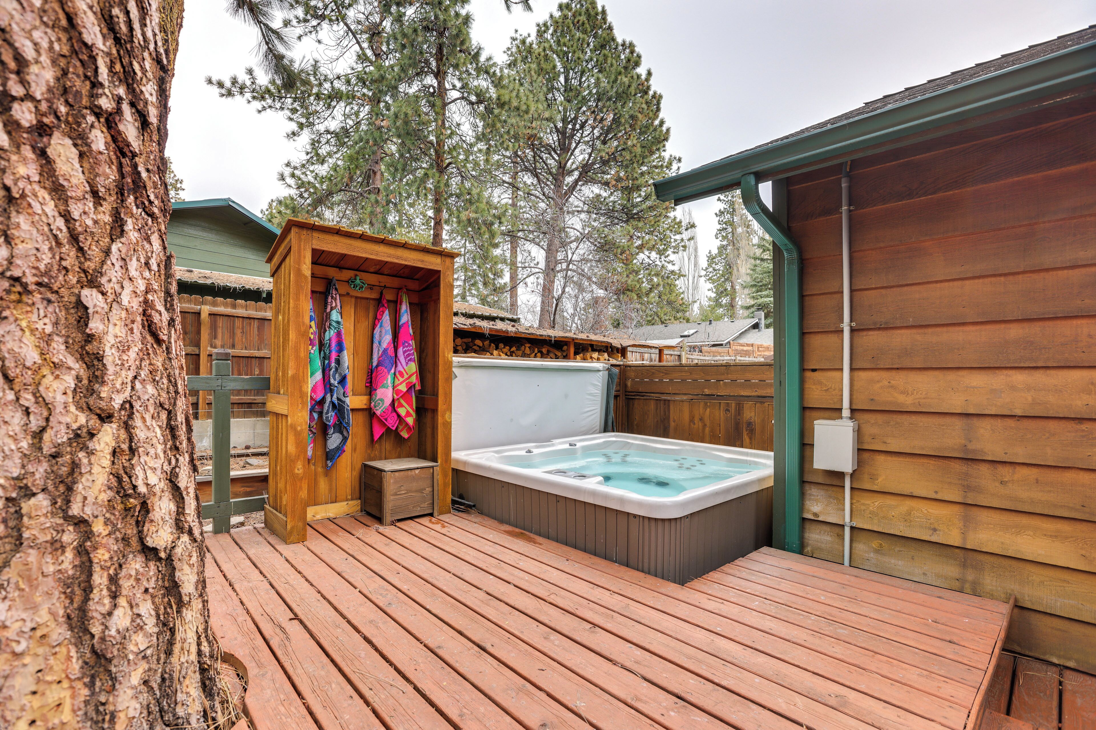 A wooden deck with a hot tub, a wooden cabin, and a tree.