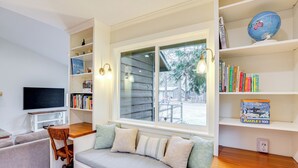 A cozy room with a built-in bench, a TV, and shelves with books and a globe.