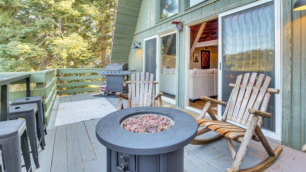 A wooden deck with a fire pit, outdoor seating, and a sliding glass door leading to an interior space. - Family-friendly Lake Arrowhead Cabin w/ Game Room! (Lake Arrowhead)