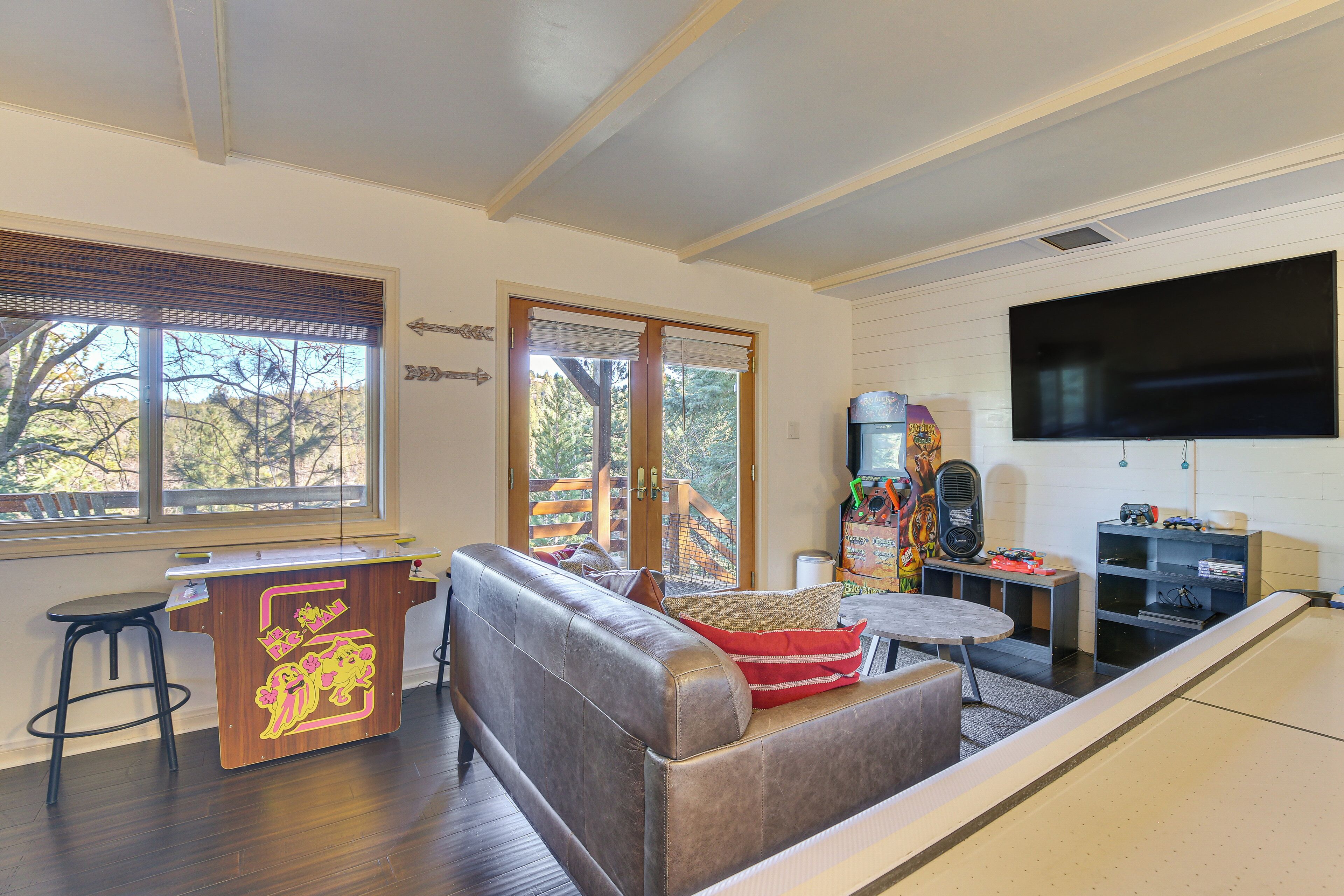 A living room with a brown leather sofa, a wooden bar counter, a television, and a large window with blinds.