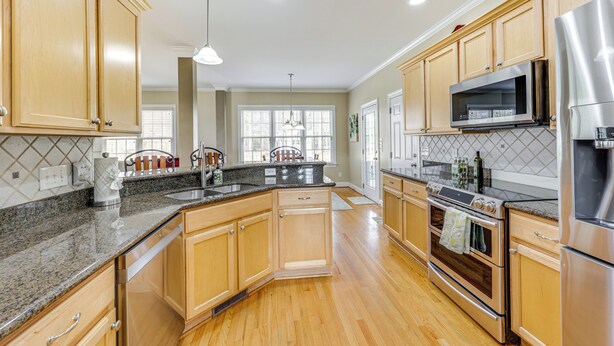 A spacious kitchen with wooden cabinets, granite countertops, stainless steel appliances, and a large window providing natural light. - < 9 Mi to Dtwn Raleigh: Family Home w/ Pool Access (Knightdale)