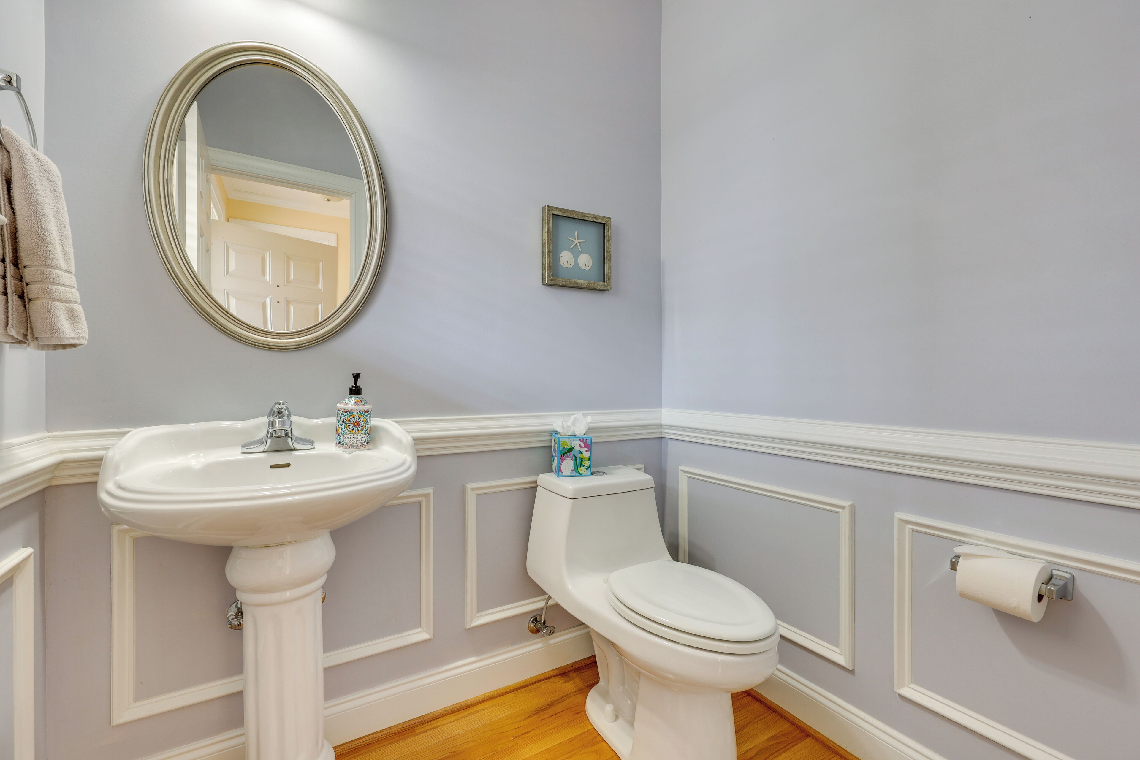 A bathroom with a pedestal sink, toilet, and a mirror.