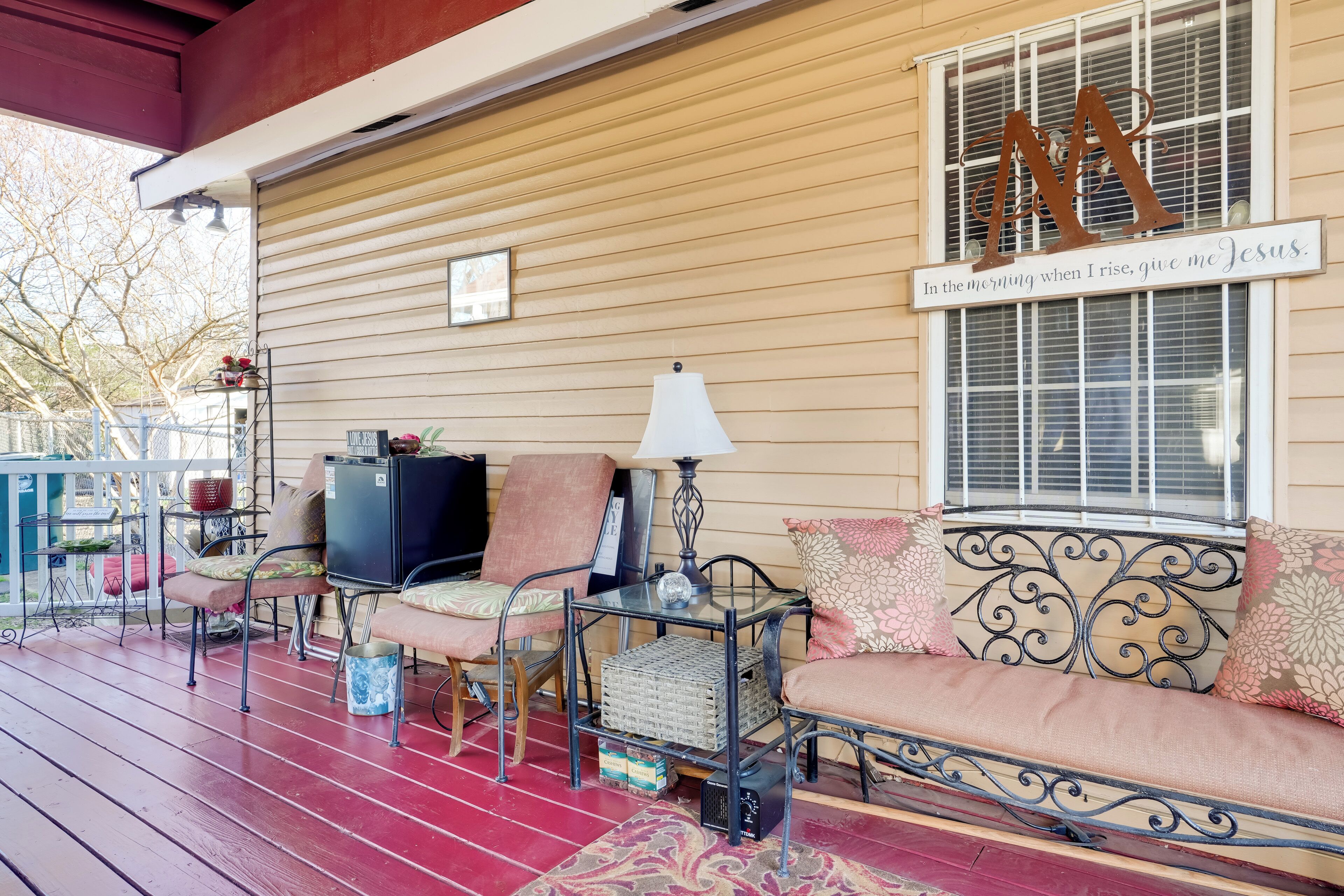 A covered porch with a bench, chairs, and a table.