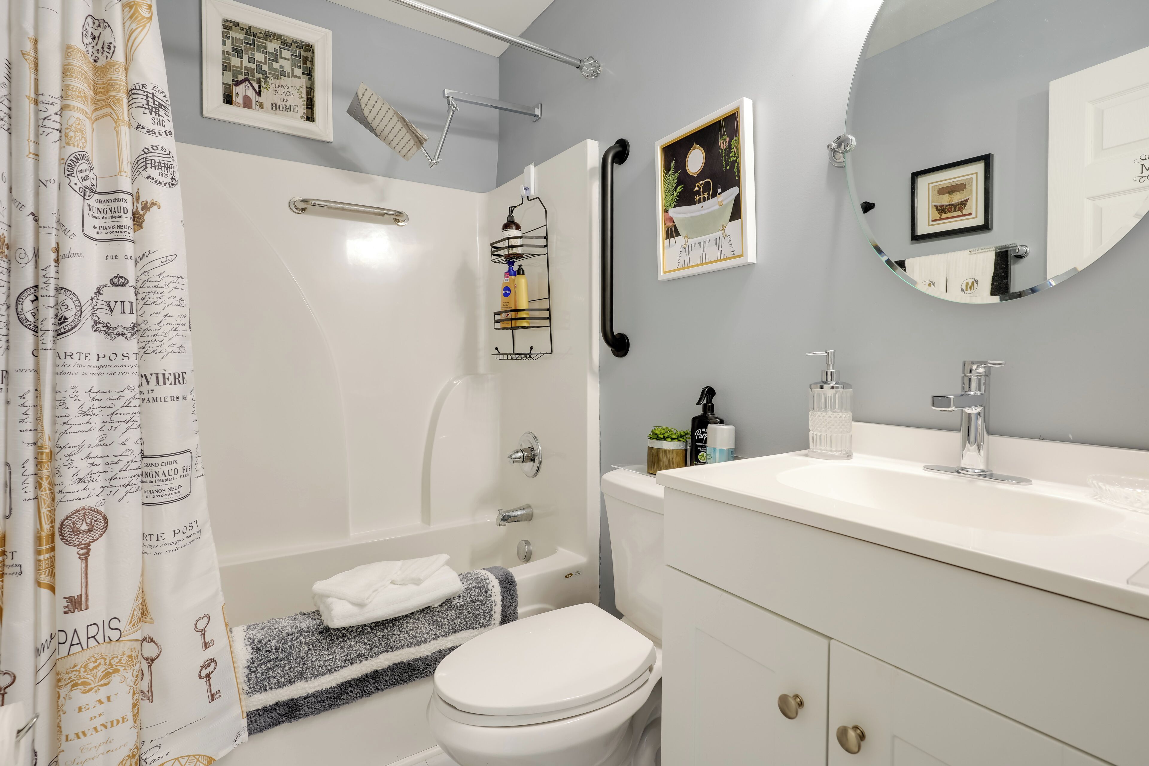 A bathroom with a bathtub, toilet, and sink. There are towels and toiletries on the sink counter.