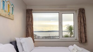 A hotel room with a bed, white bedding, a window with curtains, and a painting on the wall. - The Grottoes (Torquay)