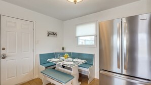 A compact kitchen with a stainless steel refrigerator, a white door, and a blue bench seating area. - Near Hunting Grounds: Quiet Home in Aspermont! (Aspermont)