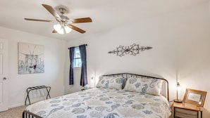 A bedroom with a bed, a ceiling fan, a bedside table with a lamp, a wall decoration, and a window with curtains. - Near Hunting Grounds: Quiet Home in Aspermont! (Aspermont)
