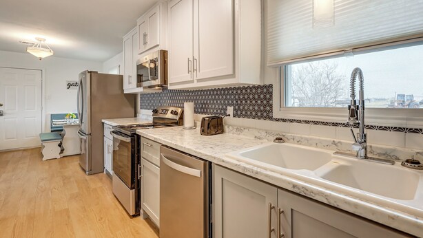 A modern kitchen with white cabinets, a stainless steel refrigerator, a built-in oven, and a double sink. - Near Hunting Grounds: Quiet Home in Aspermont! (Aspermont)