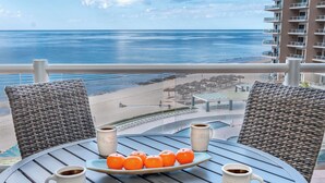 A balcony with wicker chairs, a table with a plate of oranges and two coffee mugs, overlooking a beach and ocean. - Las Palomas Phase II Coronado 503 Exceptional OceanFront 3BR 2BA Unit. (Puerto Peñasco)