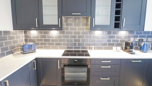 A modern kitchen with dark cabinets, a built-in oven, a stovetop, and a toaster.