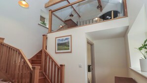 A wooden staircase leading to a loft with a glass ceiling, a framed picture on the wall, and a potted plant on the windowsill. - Cragg Lodge (Hexham)
