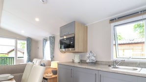 A compact kitchenette with a microwave, sink, and a cup holder. - Elton's Escape (Windermere)