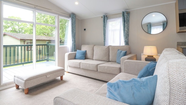 A spacious living room with a large window, a sofa set, a round mirror, and a lamp. - Elton's Escape (Windermere)