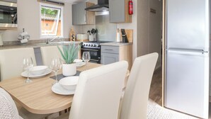 A modern kitchen with a dining area, including a table set for two, a stove, and a refrigerator. - Elton's Escape (Windermere)