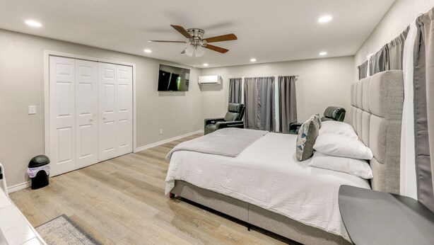 Une chambre à coucher avec un lit, un ventilateur de plafond, une télévision et un bureau avec une chaise.