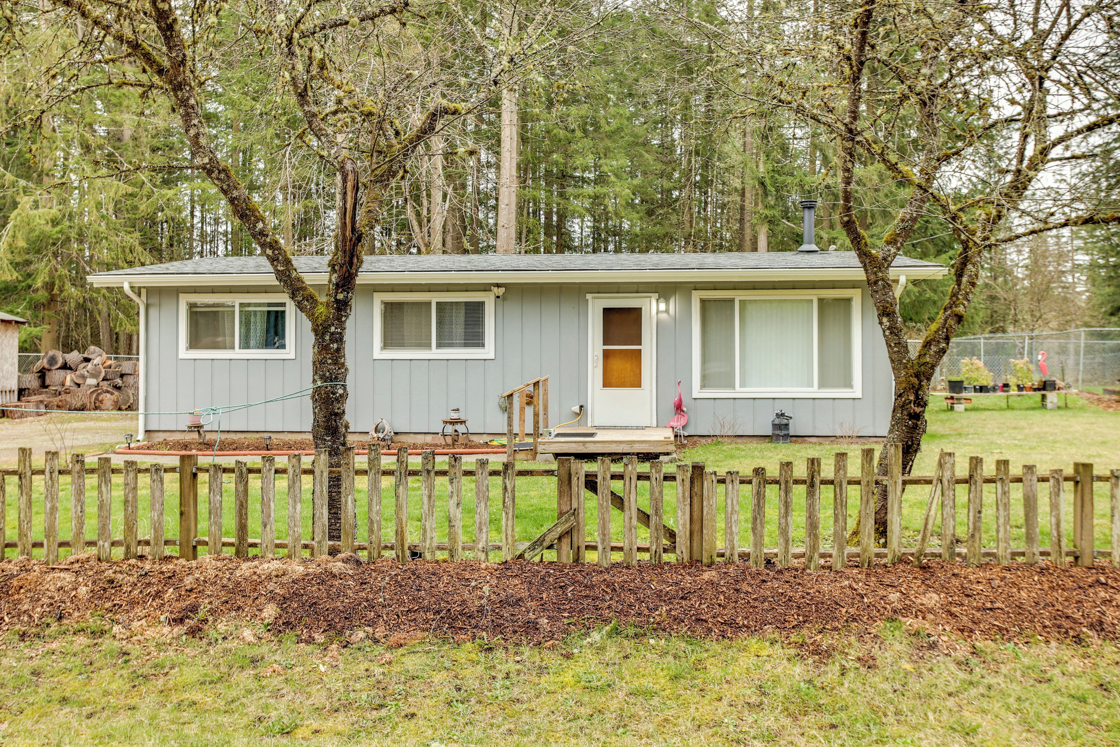 A small, single-story house with a front porch, a fenced yard, and a wooden deck.