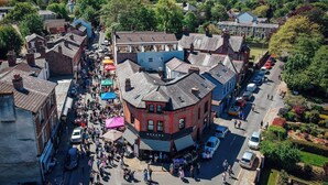 A bustling street scene with a mix of residential and commercial buildings, including a prominent red brick building with a sign that reads "GREEN'S". - Modern 1-bed Apartment - Sleeps 4 & Central Links (Birkenhead)