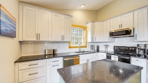 A modern kitchen with white cabinetry, a granite countertop, stainless steel appliances, and a window with a view. - Dog Friendly Mountain View Retreat w/ Hot Tub (Purlear)