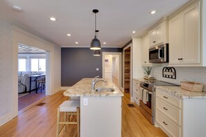 A modern kitchen with white cabinets, a granite countertop, stainless steel appliances, and a pendant light. - 3 Mi to Dtwn Greer: Mountain-view Home! (Greer)