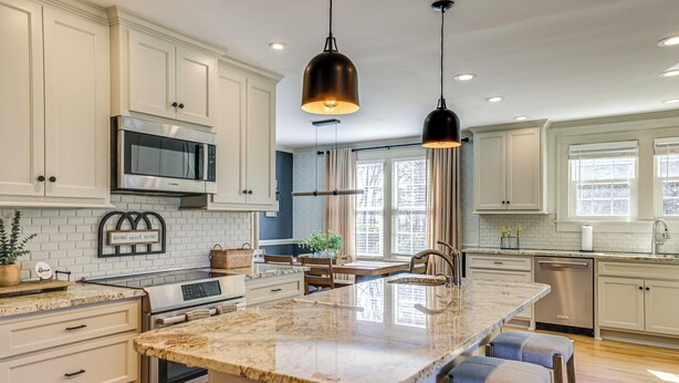 Una cocina moderna con armarios blancos, electrodomésticos de acero inoxidable y una isla grande con taburetes de bar.