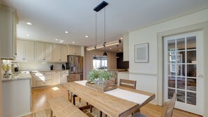 Una cocina moderna con armarios de madera, una isla central y una zona de comedor con banco y sillas.