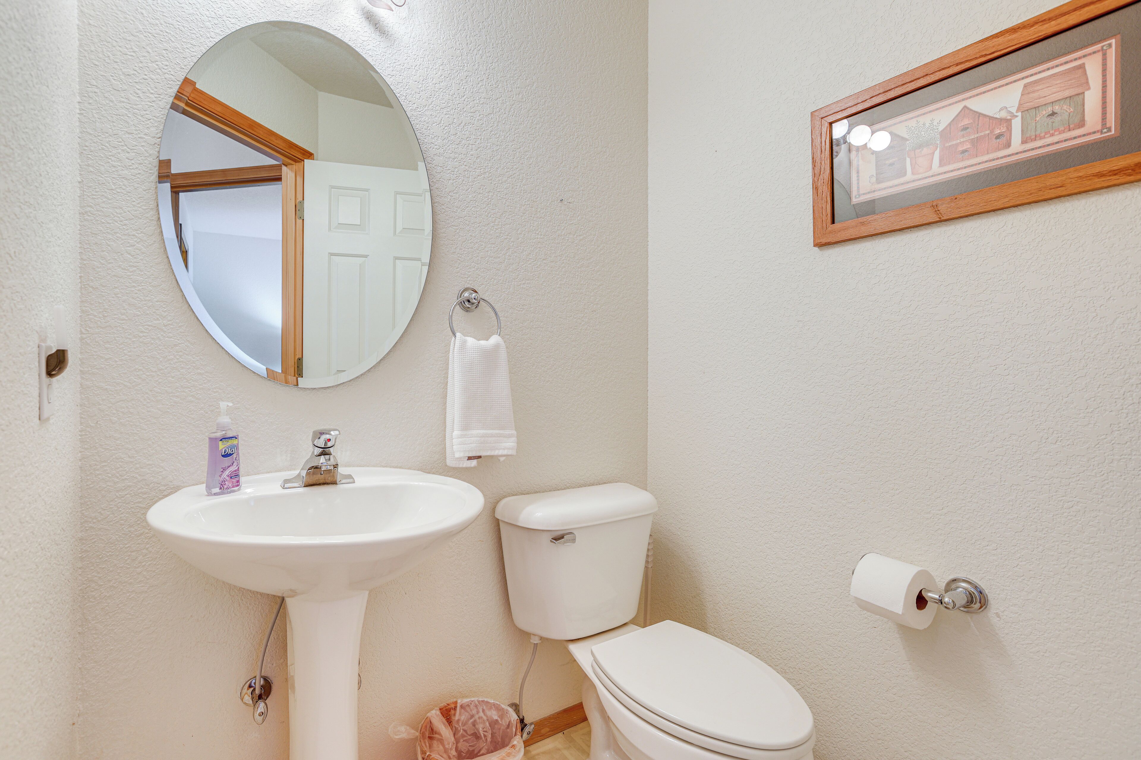 Een badkamer met een wit wastafel, toilet en een fotokader aan de muur.