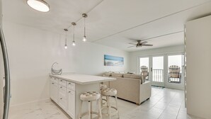 A modern kitchen with a white island, bar stools, and pendant lighting. - Dogs Welcome: Beachfront South Padre Island Condo (South Padre Island)