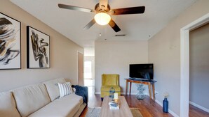 A living room with a sofa, a coffee table, a TV, and a ceiling fan. - 3 Mi to Dtwn Denton: Getaway w/ Furnished Patio! (Denton)