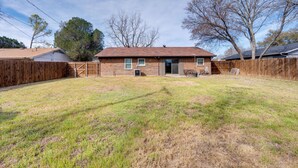 A single-story brick house with a fenced backyard, a front door, and a small porch. - 3 Mi to Dtwn Denton: Getaway w/ Furnished Patio! (Denton)