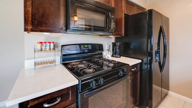 A kitchen with dark wooden cabinets, a stainless steel stove, a black refrigerator, and a microwave above the stove. - 3 Mi to Dtwn Denton: Getaway w/ Furnished Patio! (Denton)