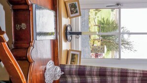 Una habitación con un escritorio de madera, cortinas a cuadros y una ventana que da a vistas de vegetación.