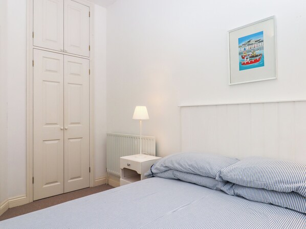 Une chambre à coucher avec un lit, une table de chevet, une lampe et une armoire.