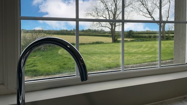 A window with a view of a grassy field and trees. - Narrow Gauge Cottage (Ballymoney)
