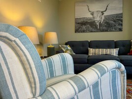 Una sala de estar con un sillón a rayas, un sofá oscuro y una lámpara.