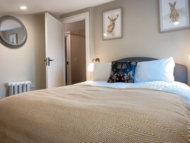 Un dormitorio con una cama grande, un espejo redondo y dos cuadros en la pared.