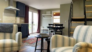A compact living space with a kitchen, dining area, and a loft bedroom. - Narrow Gauge Cottage (Ballymoney)