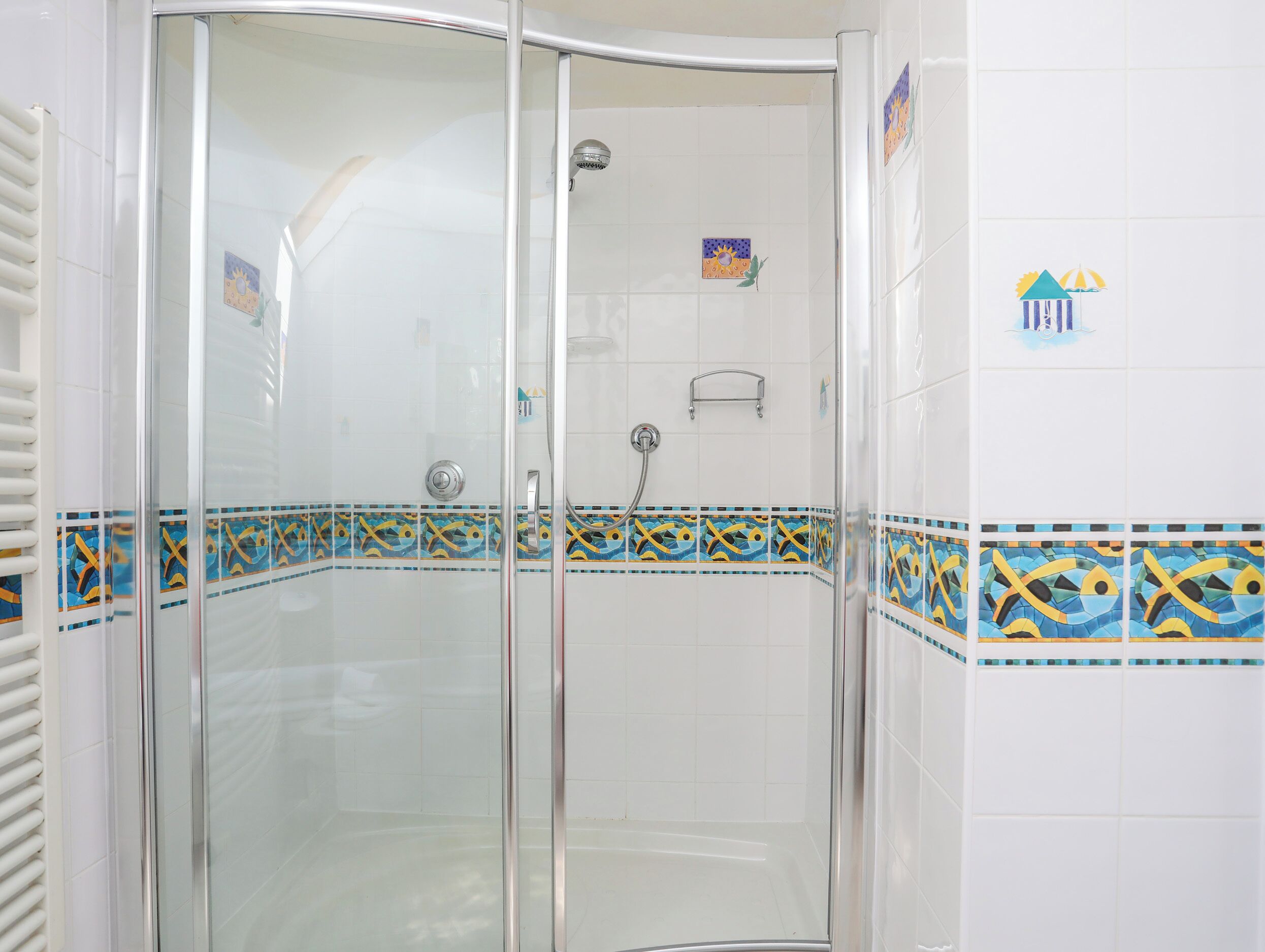 Eine begehbare Dusche mit Glastüren und einer mit dekorativen Mustern versehenen Fliesenwand.